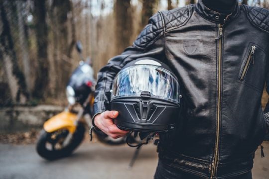 Closeup of a motorcyclist carrying a helmet under their arm